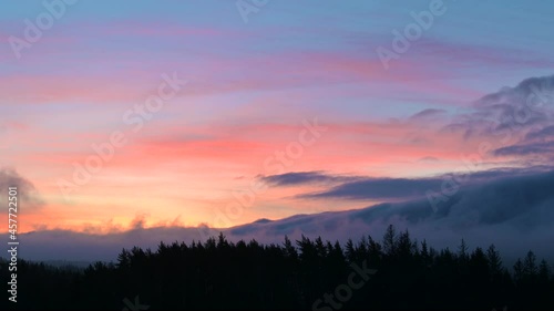 Mystical sunrise with fog in forest and burning sky
