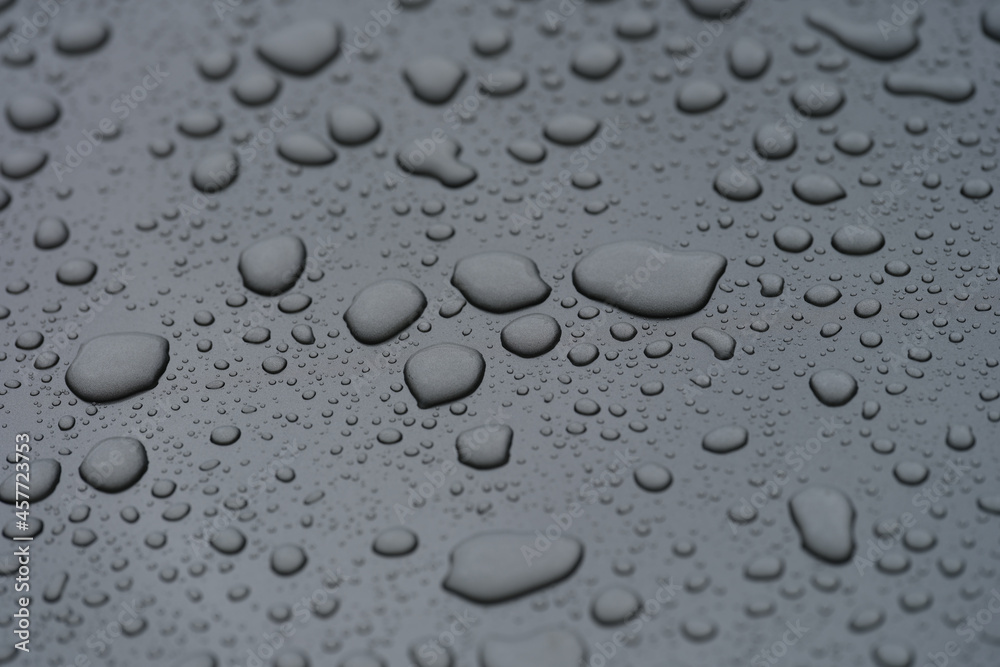 Closeup of raindrops on black hood of car background Closeup of raindrops on black hood of car background
