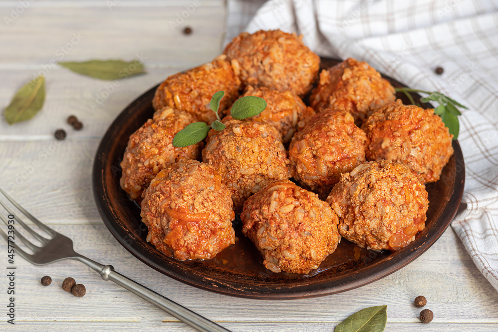 Meat balls on a light background with sage and parsley leaves. Homemade lunch.