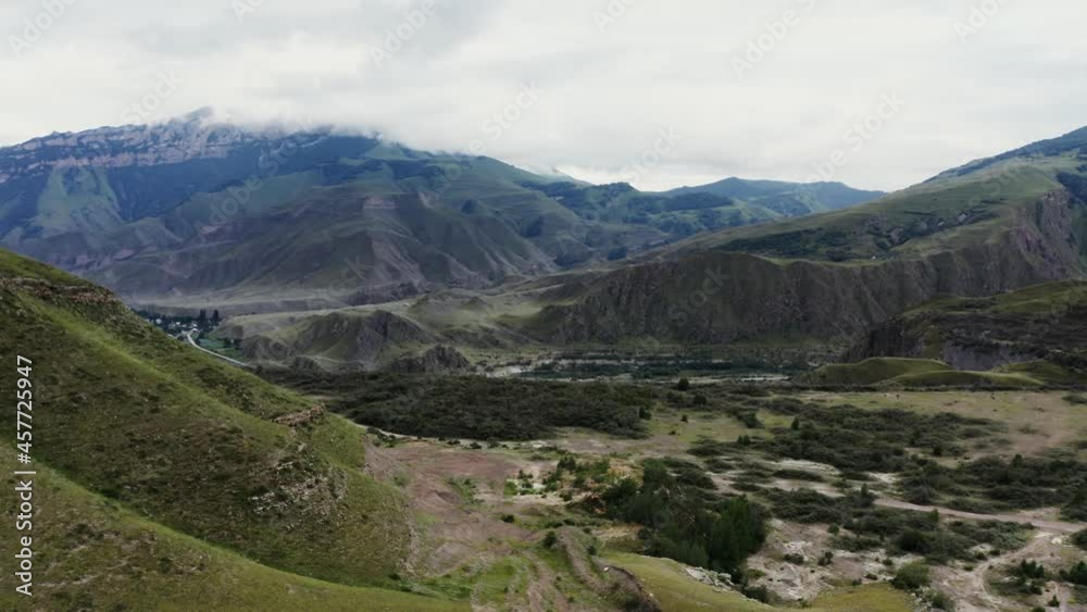 town and river in lowland among hills covered with forest at foot of mountains town and river in lowland among hills covered with forest at foot of mountains