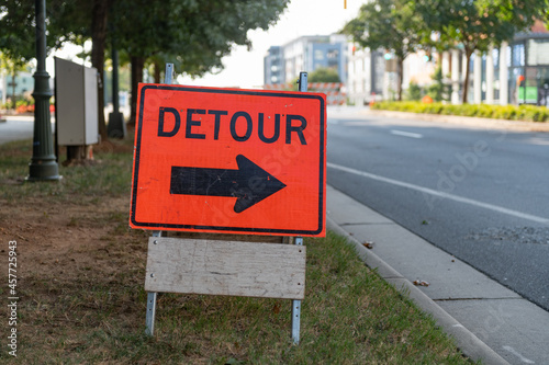 Orange and black detour sign with bold arrow on a city street photo