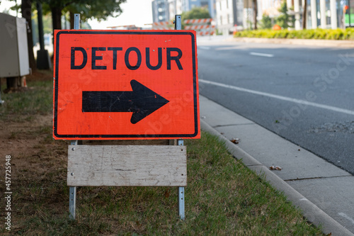 Orange and black detour sign with bold arrow on a city street