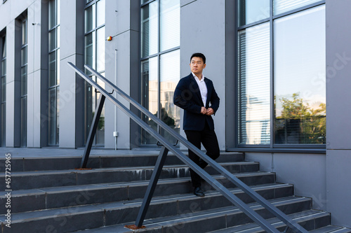 Asian businessman walks up the stairs of the office center, man hurries to a business meeting in a suit