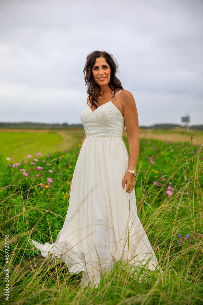 Junge hübsche Frau im Brautkleid in einer Blumenwiese Junge hübsche Frau im Brautkleid in einer Blumenwiese