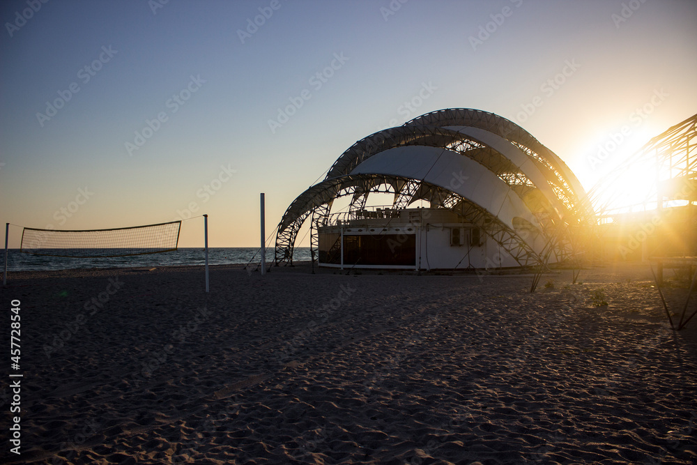 Obraz premium Art stage for the performances of artists in white against the backdrop of a sunset with sand and a voleyball net.