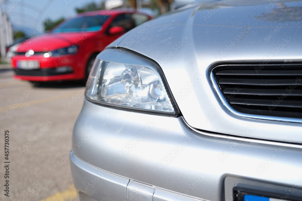 Closeup of clean headlights of silvery car in parking