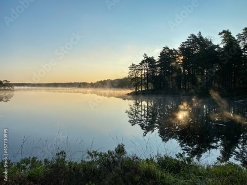 Sunrise over a lake in Sweden with water reflections an a clear blue sky - Landscape Photography