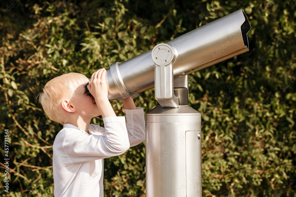 Child looks into a large telescope. Observation of nature through a telescope
