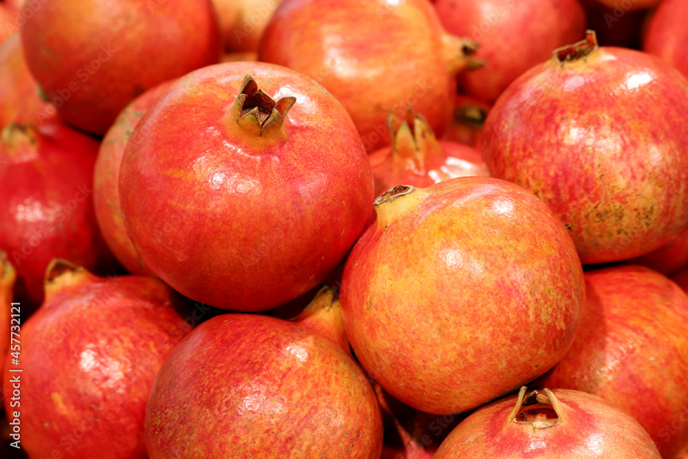 Ripe pomegranates close up, selective focus. Red pomegranate fruits on the market, natural background Ripe pomegranates close up, selective focus. Red pomegranate fruits on the market, natural background