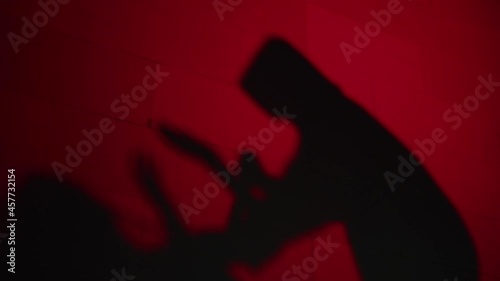 Creepy death silhouette killing victim with knife on red background. Mystical scary murderer, maniac murdering woman. Halloween costume of killer. Horror scene movie of psycho serial. 