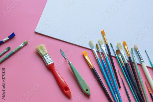 Paintbrushes and white canvas on pink paper background. Education, school and art concept. Free space for text or image
