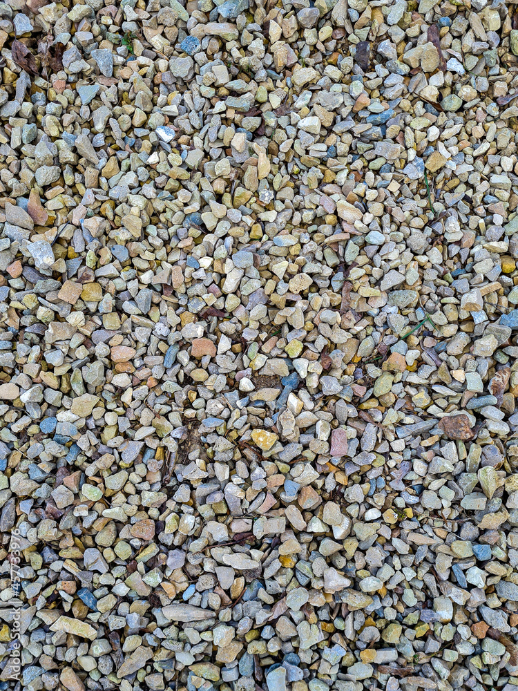Multicolored small stones are evenly scattered and create a beautiful small stone background. Daylight. View from above Multicolored small stones are evenly scattered and create a beautiful small stone background. Daylight. View from above