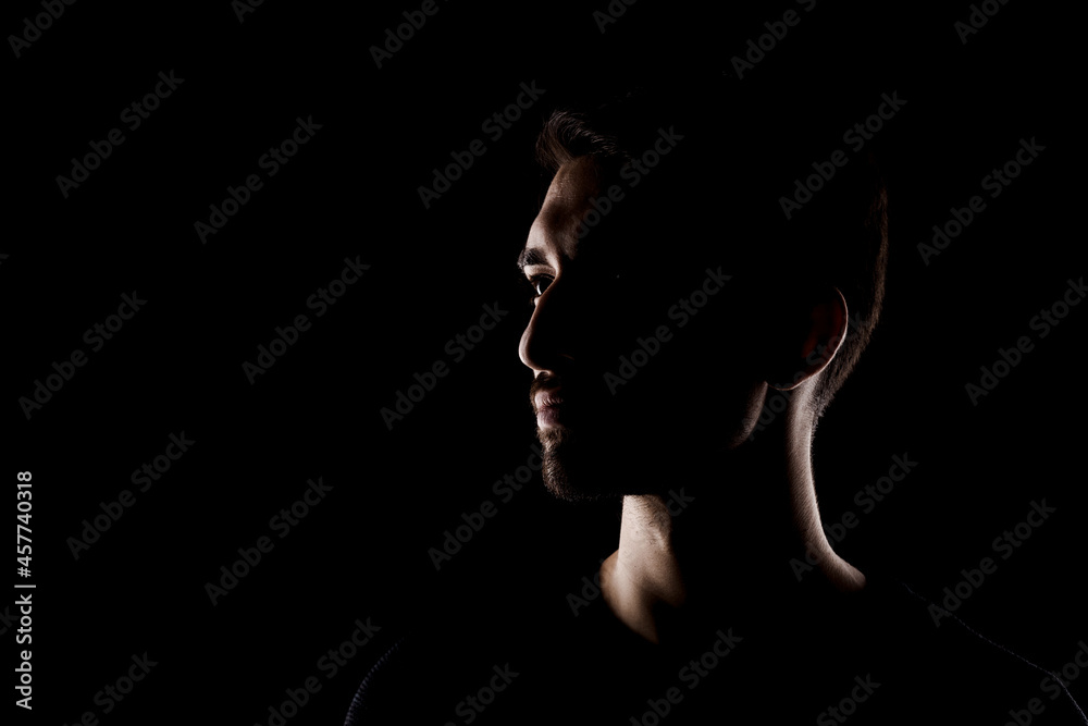 Side lit contour portrait of young handsome male with short beard