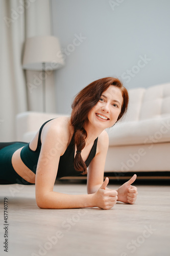 Woman in sportswear is engaged in fitness at home doing plank yoga exercises.Concept of health and sports.