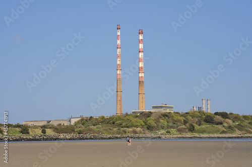 Beautiful closeup bright view of iconic Poolbeg power station chimneys and Poolbeg CCGT station against clear blue sky seen from Sandymount Beach, Dublin, Ireland. Soft colors. Copy space