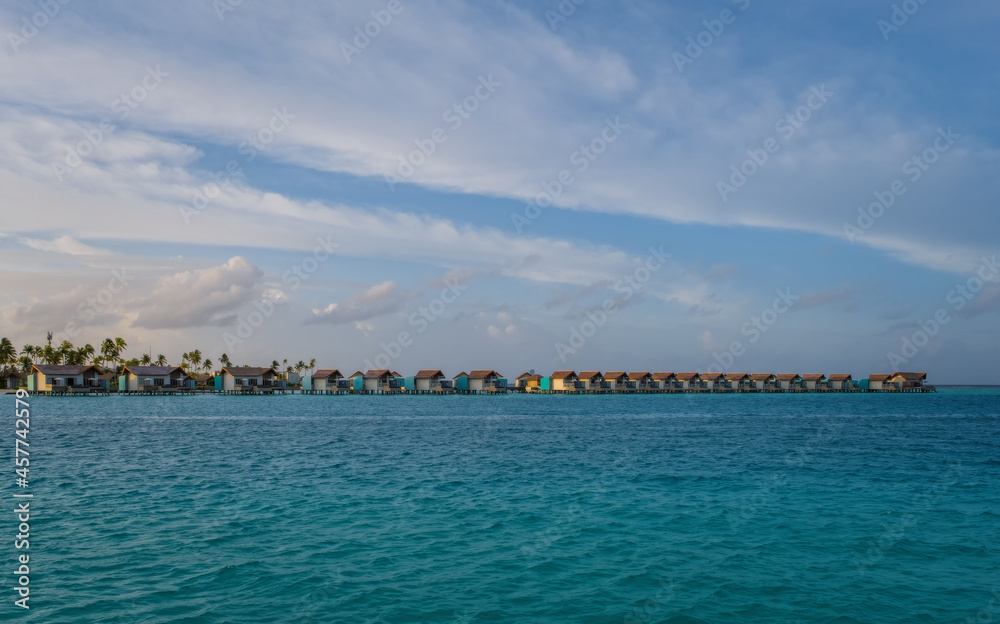 Fototapeta premium Island in ocean, overwater villas at the sunrise. Crossroads Maldives, july 2021
