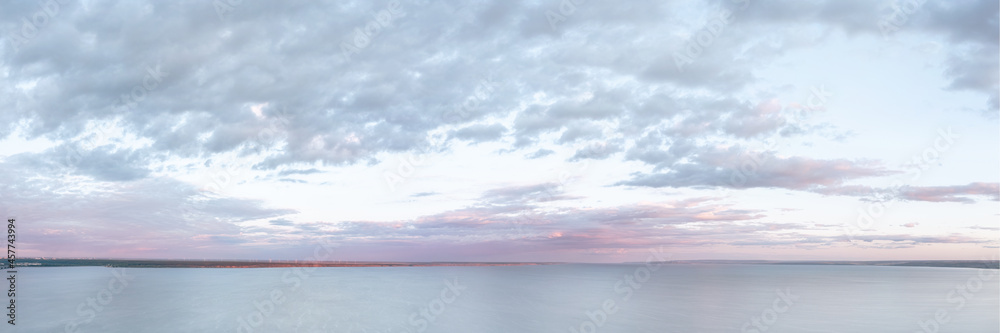 Large dramatic pastel colored cloudscape over large river at sunset