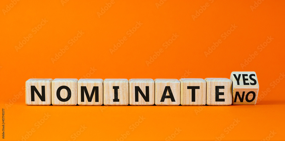 Nominate symbol. Turned a wooden cube and changed words 'nominate no' to 'nominate yes'. Beautiful orange background. Business and nominate concept, copy space.