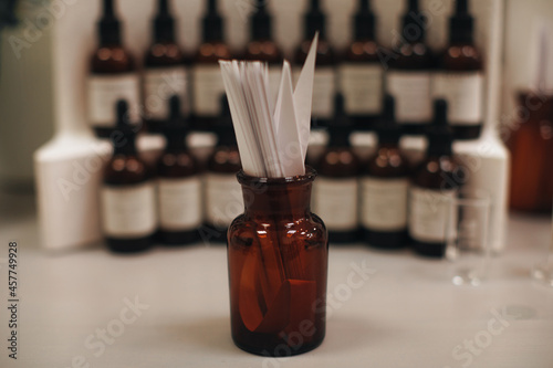 Mockup brown glass bottle with blotter paper for testing smell of essential oil and fragrance oil. Perfume tester paper strips. photo