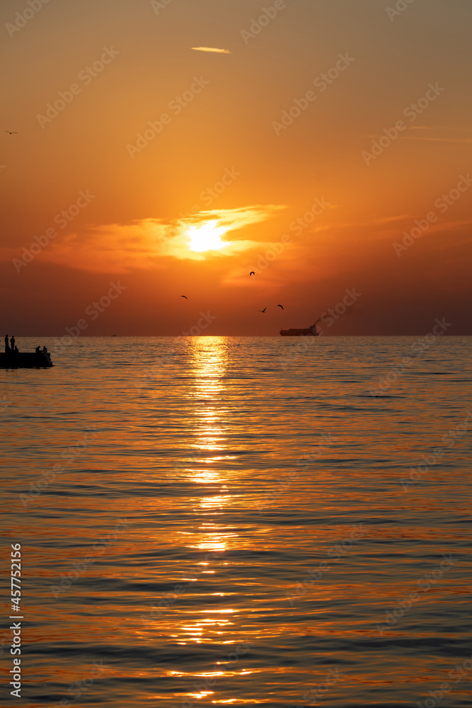 sunset in trieste with silhouette of birds fish and people on the pier