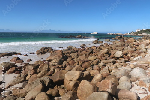 Scenic turquoise Indian ocean water along sandy beach with large granite boulders near Simons's town, on the Cape Peninsula, Cape Town, South africa