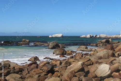 Scenic turquoise Indian ocean water along sandy beach with large granite boulders near Simons's town, on the Cape Peninsula, Cape Town, South africa