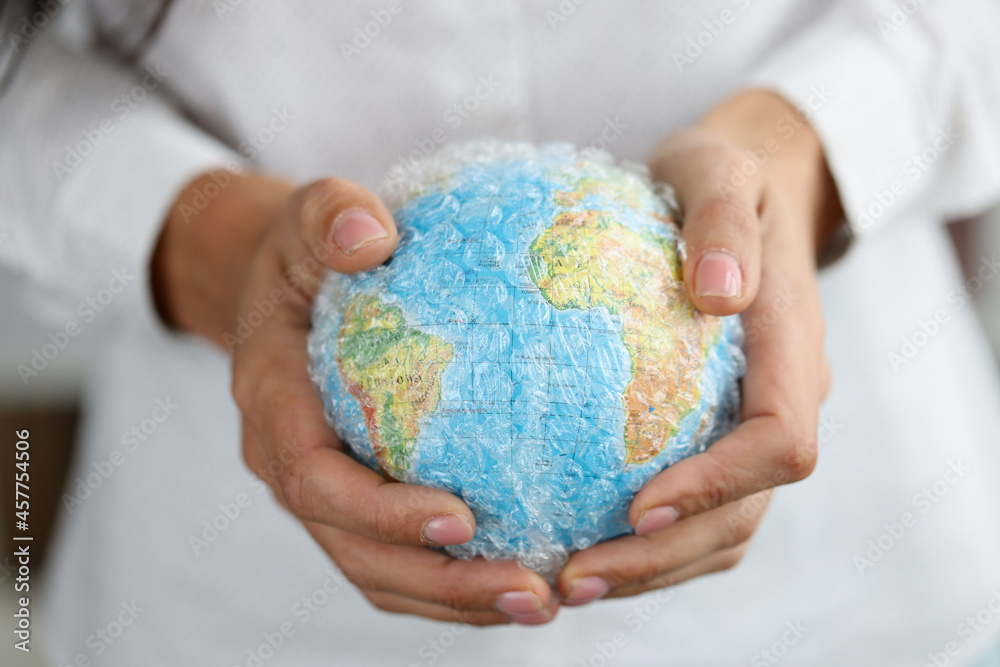 Woman holds plastic covered globe showing environmental problems Woman holds plastic covered globe showing environmental problems