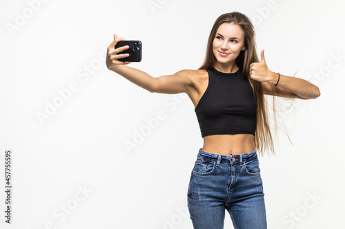 Happy young woman showing thumb up and making selfie on smartphone.