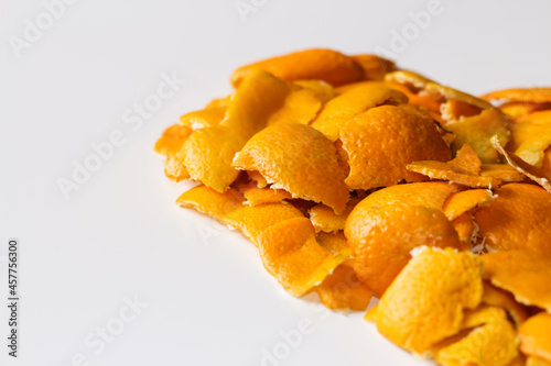 Close up is a pile of dried orange and tangerine skins. On a white background. Lots of small pieces of dried orange peel, stacked together. Good New Year spirit. Selective focus