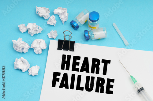 On a blue background, a syringe, white crumpled pieces of paper and a sheet with the inscription - HEART FAILURE