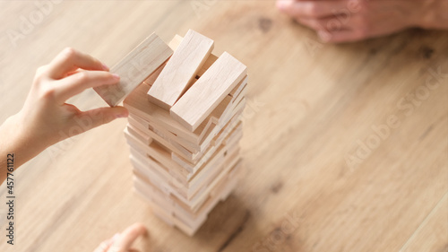 Father and son playing wooden block removal tower game at home together. Board game Jenga. Kids leisure concept.