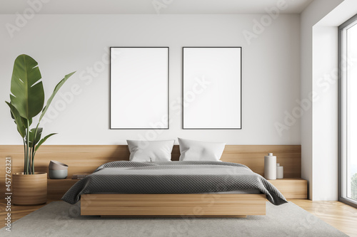 Bright bedroom interior with large bed, two empty posters © ImageFlow