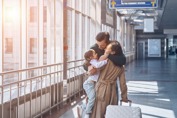 Happy family embracing and smiling while reuniting at the airport terminal