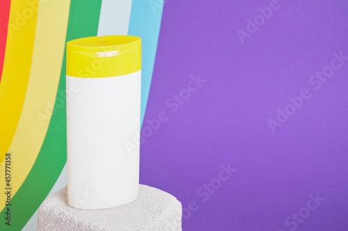 white plastic bottle on cocrete podium on rainbow background