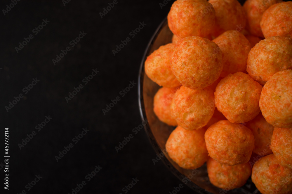 Cheese snack from a glass pot with cheese sticks and cheese balls on a black wooden table