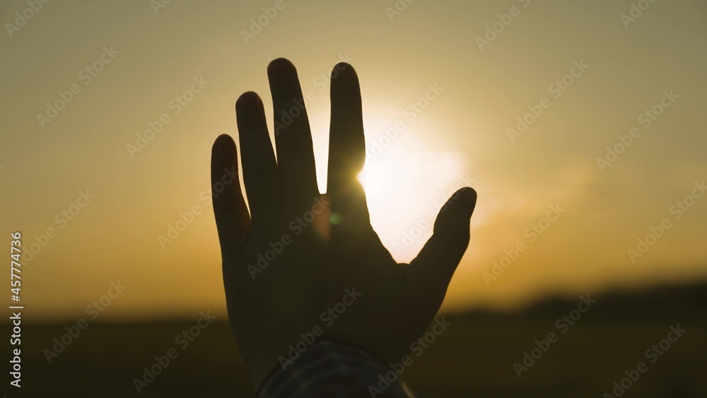 silhouette of a human hand at sunset, asking the sky for help, believing in a dream, the glare of the sun in the sky, a walk and evening rest in a tourist trip, praying to God