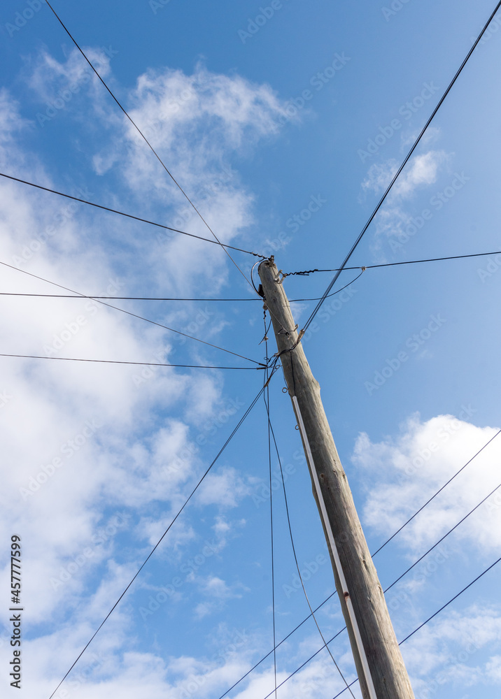Wooden utility pole and electricity power lines, against a blue sky Wooden utility pole and electricity power lines, against a blue sky