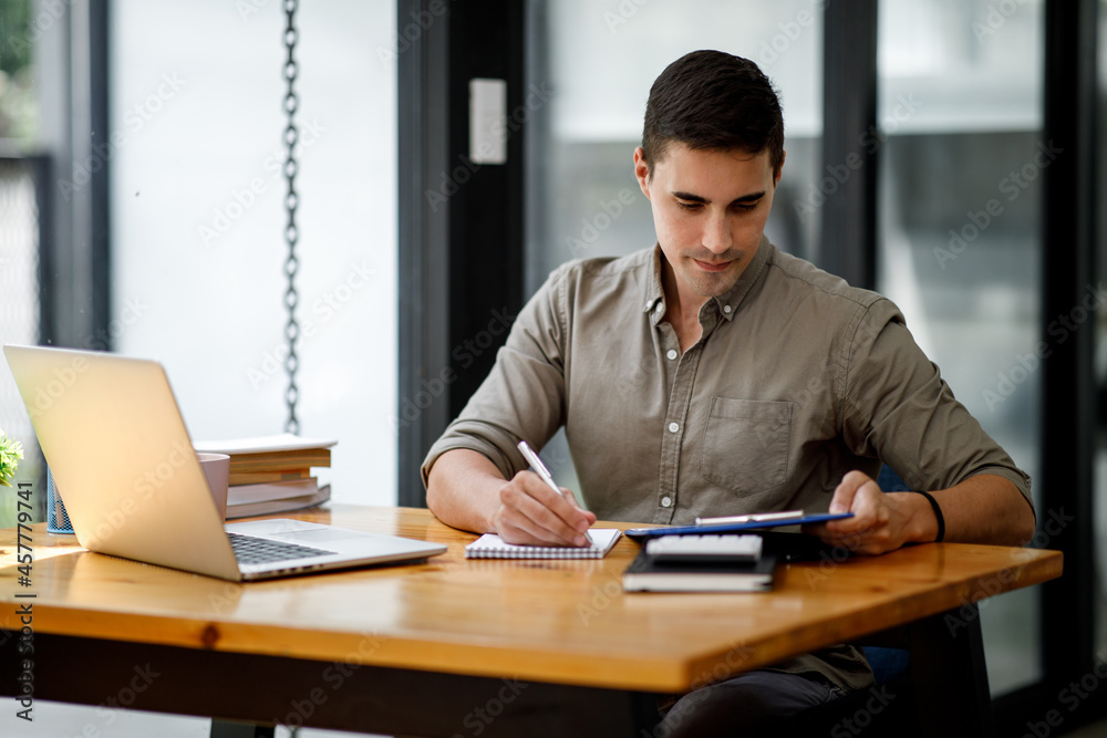 Young handsome man or businessman working on laptop computer in modern office.doing finances,accounting analysis,report,data and pointing graph Freelance education and technology concept. Young handsome man or businessman working on laptop computer in modern office.doing finances,accounting analysis,report,data and pointing graph Freelance education and technology concept.