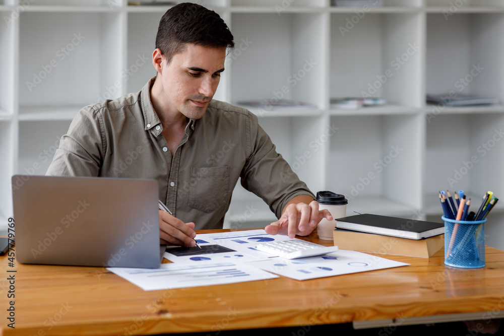 Young handsome man or businessman working on laptop computer in modern office.doing finances,accounting analysis,report,data and pointing graph Freelance education and technology concept. Young handsome man or businessman working on laptop computer in modern office.doing finances,accounting analysis,report,data and pointing graph Freelance education and technology concept.