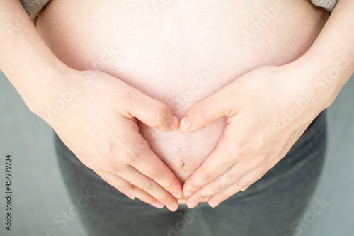Wallpaper Mural A young pregnant Asian woman making a heart mark by hand Torontodigital.ca