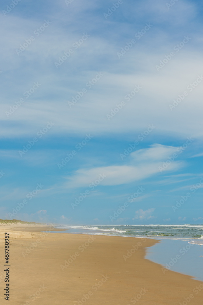 sand beach and blue sky. vertical orientation. copy space.