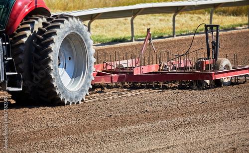 Tractor pulling a harrow on a dirt track