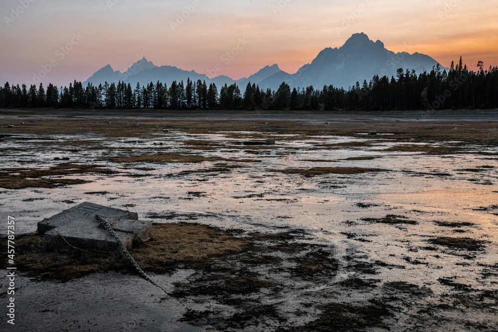Obraz premium View of silhouetted mountains and trees in Grand Teton National Park, Wyoming during sunset.