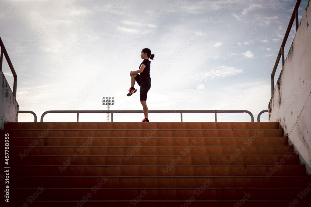running woman stretching during morning exercise on the stadium stairs health care concept