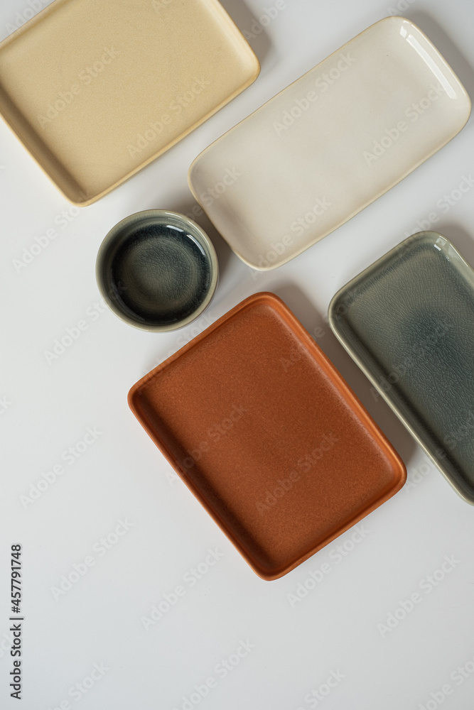 Neutral colour handmade ceramics, empty craft ceramic plates and bowls on white background. Flat lay, top view Neutral colour handmade ceramics, empty craft ceramic plates and bowls on white background. Flat lay, top view