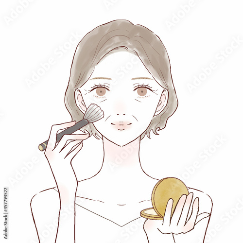 パウダリーファンデーションをメイクブラシで顔に塗る中年女性