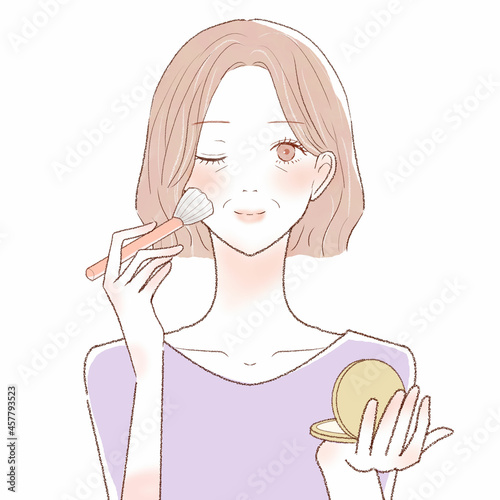 パウダリーファンデーションをメイクブラシで顔に塗る中年女性