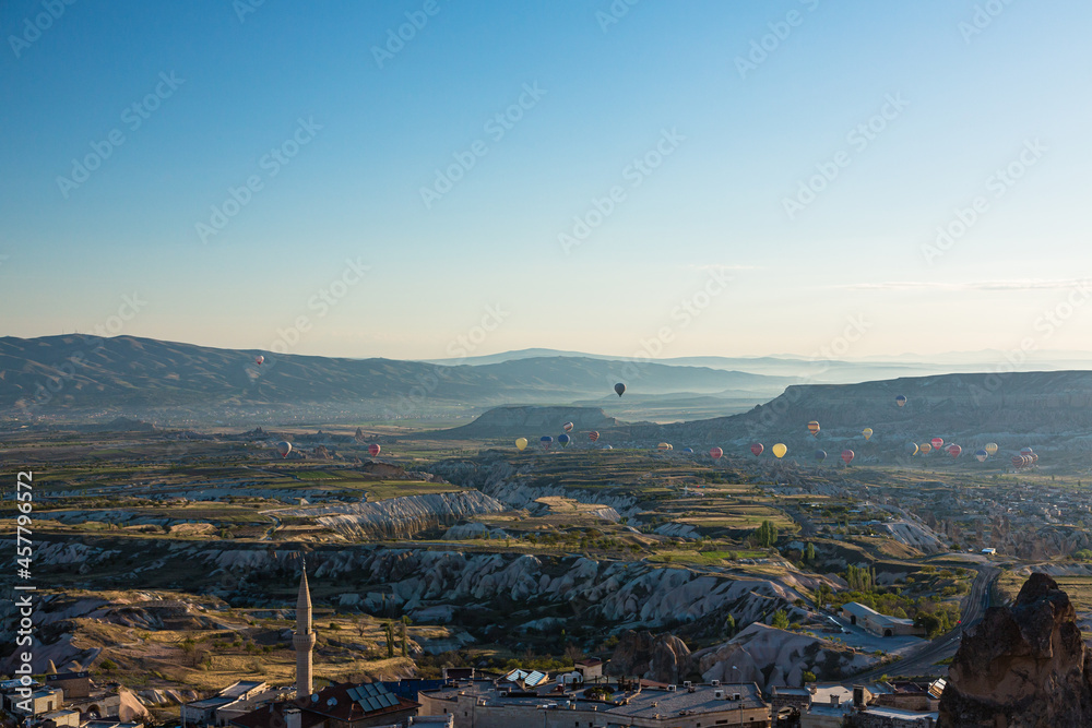 トルコ　カッパドキアのウチヒサール城から見える奇岩群と洞窟住居とギョレメ国立公園の空を飛ぶ熱気球