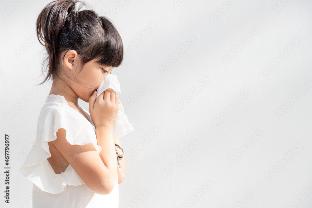 Asian child girl sick with sneezing on the nose and cold cough on tissue paper because weak or virus and bacteria from dust weather Asian child girl sick with sneezing on the nose and cold cough on tissue paper because weak or virus and bacteria from dust weather