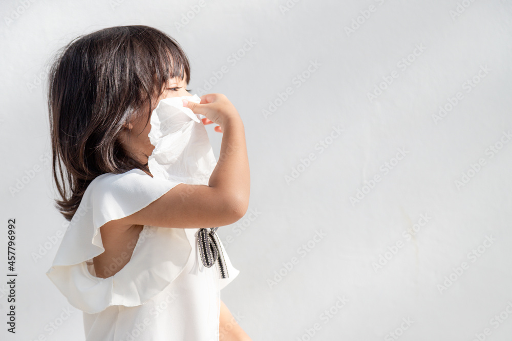 Asian child girl sick with sneezing on the nose and cold cough on tissue paper because weak or virus and bacteria from dust weather and kindergarten and preschool